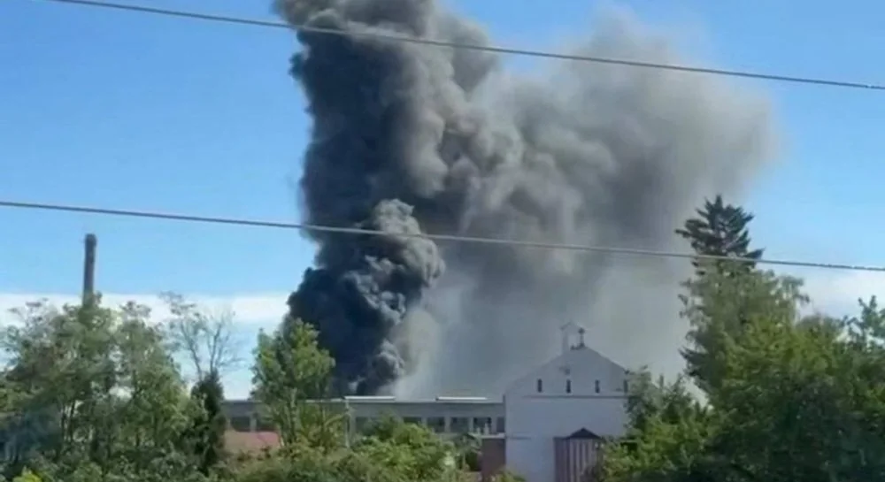 Великий стовп чорного диму над будівлями заводу серед дерев у Львові