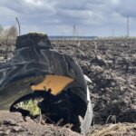 Чорні обгорілі уламки боєприпасу серед зораного поля під хмарним небом