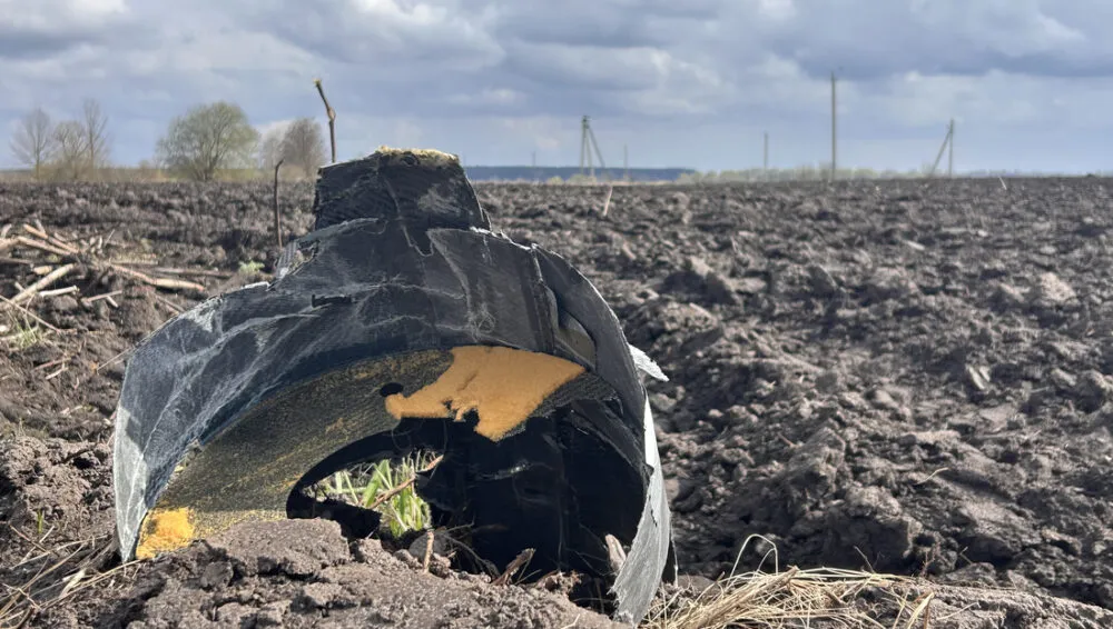 Чорні обгорілі уламки боєприпасу серед зораного поля під хмарним небом