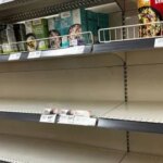 Порожні полиці супермаркету з пачками круп і цінами на верхній полиці